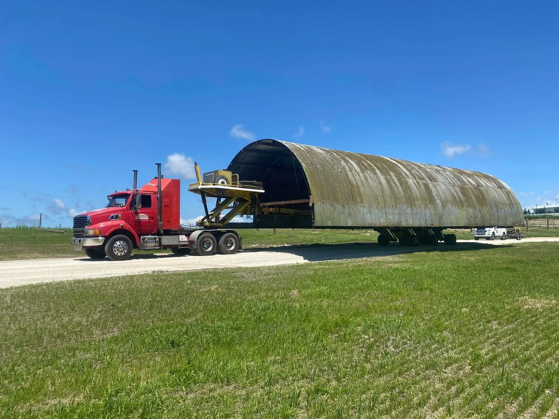 Large curved aircraft hangar and barn relocation across farmland